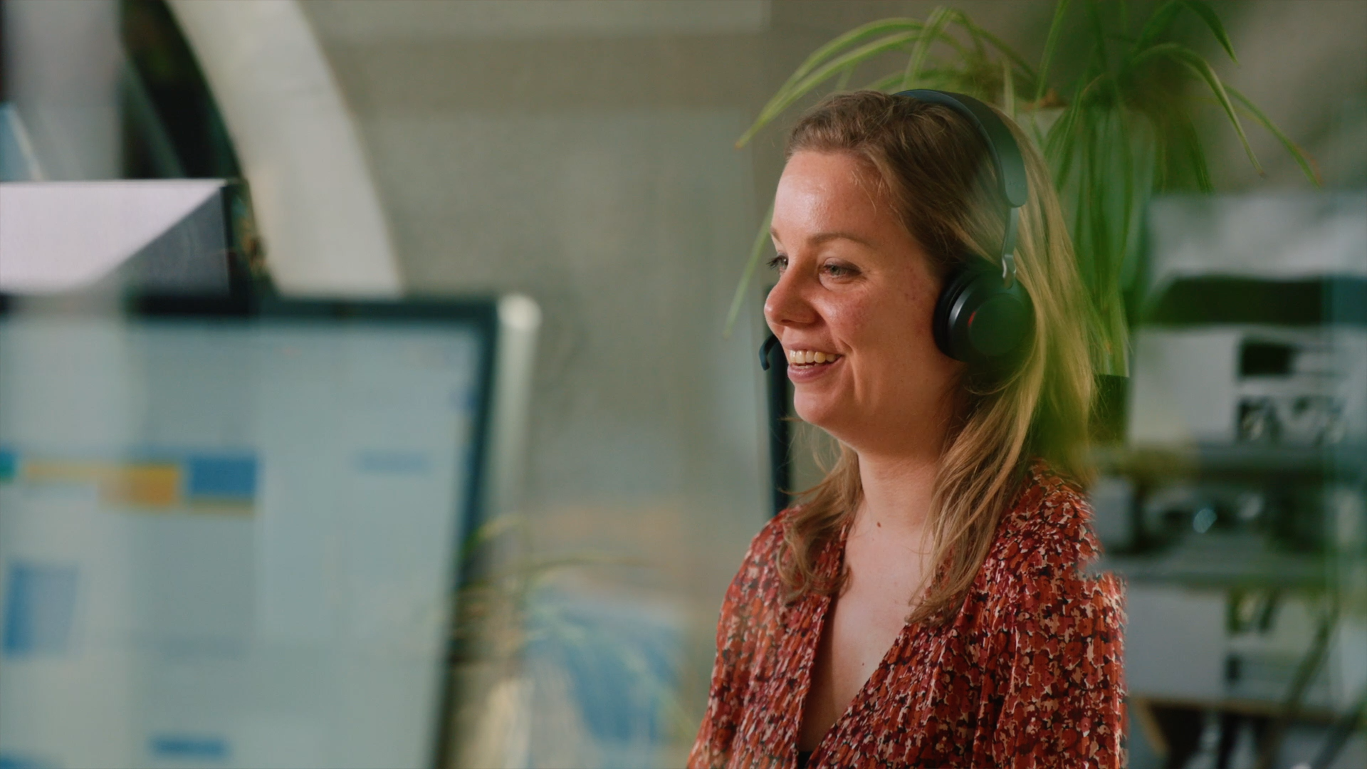 Gripp - Testimonial || Full Frame - Creative Content Partner, medewerkster achter een bureau met een headset op en een lach