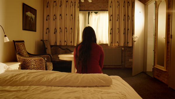 tienermeisje met een rode trui in een beige hotelkamer